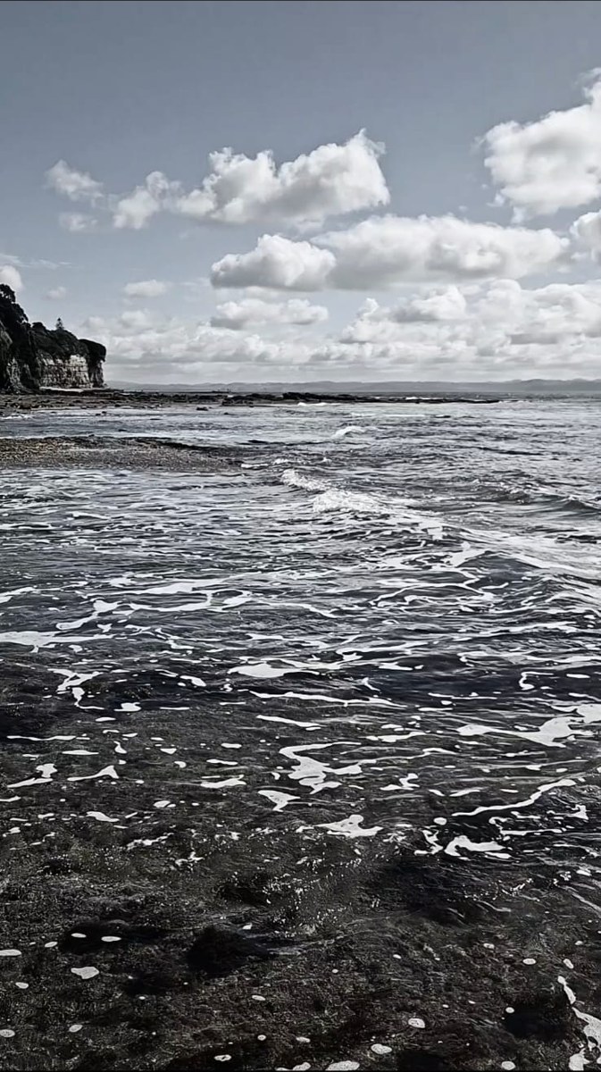 Black and white surf washing over a rocky shoreline
