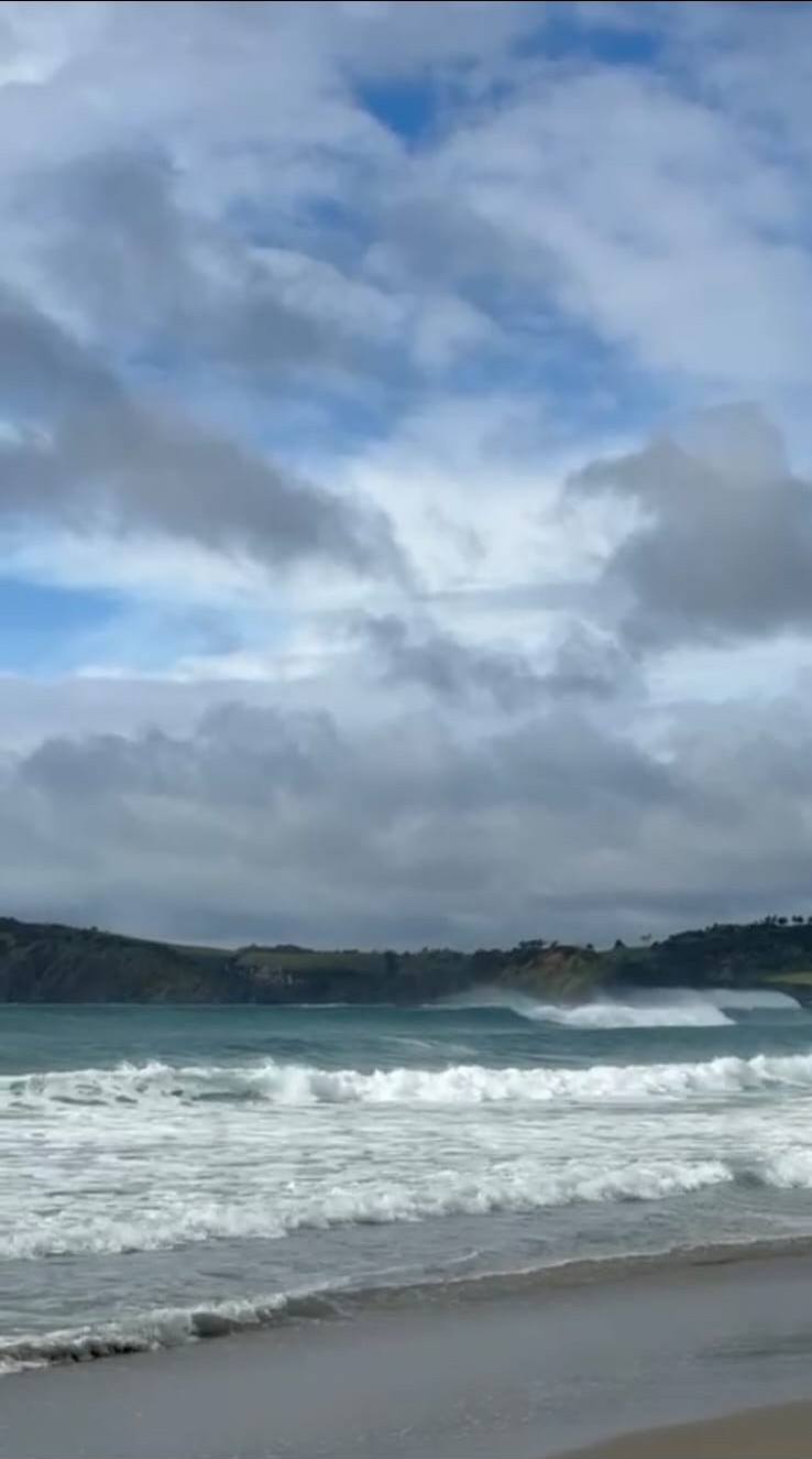 Ocean waves rolling toward shore beneath dramatic clouds