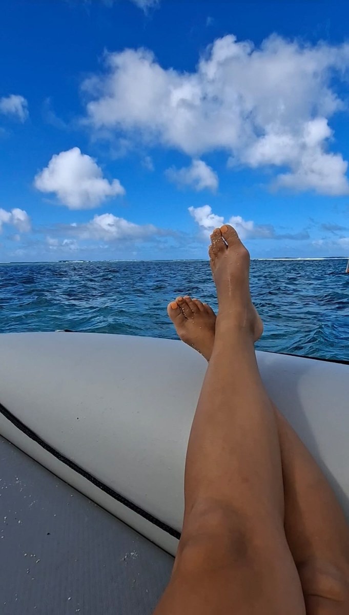 Feet up on the edge of a boat over deep blue lagoon water
